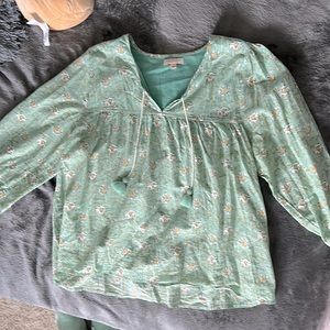 This is a beautiful light, green blouse with the flowers fits like a medium